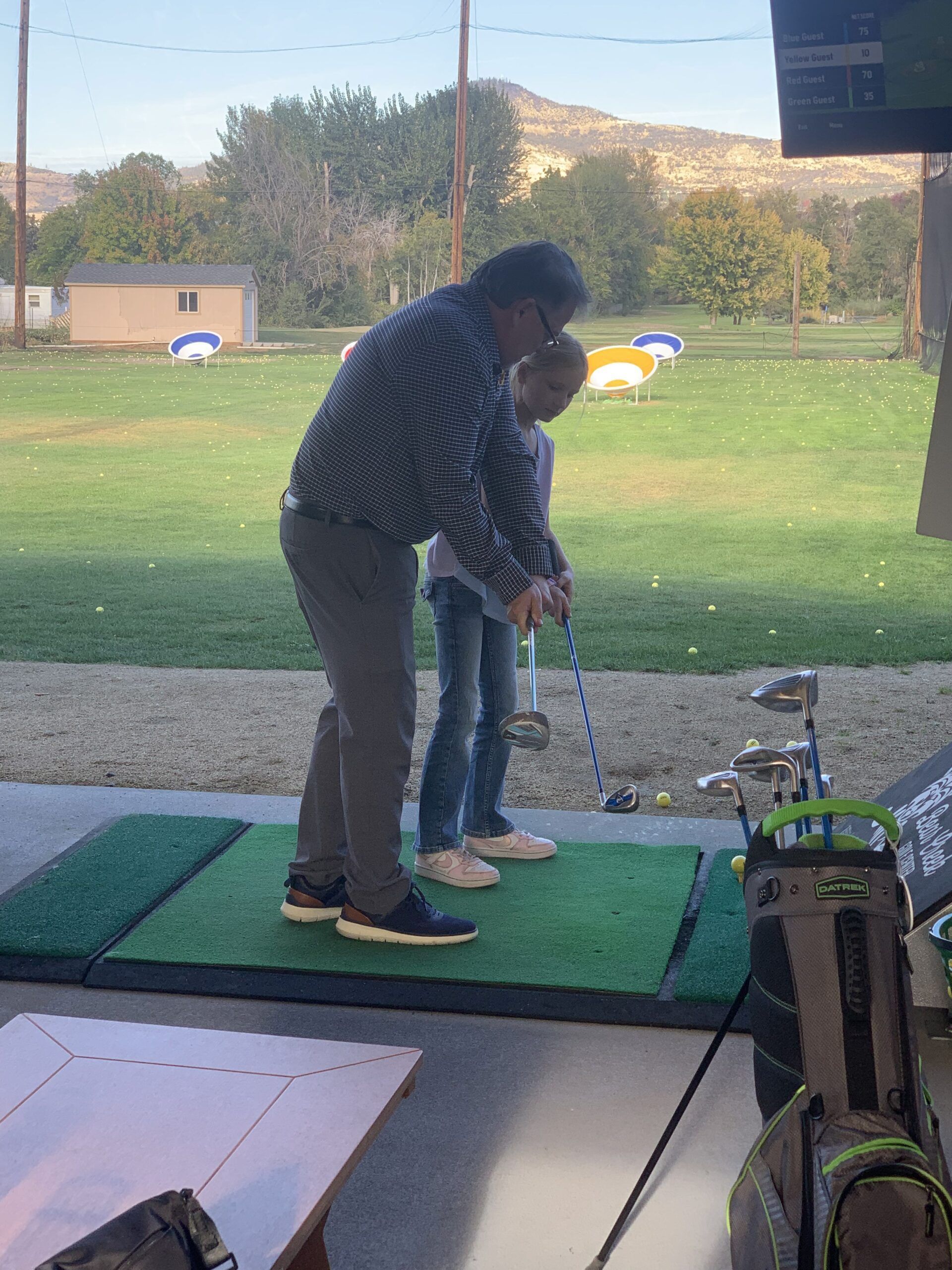 John Warekois helping a girl tee off at top golf