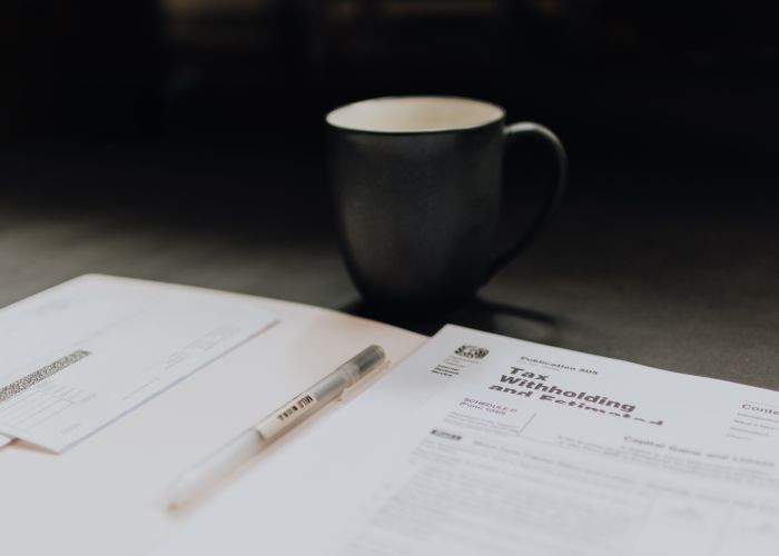 Coffee mug and Tax Withholding papers on table